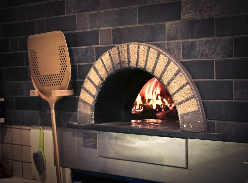 Brick pizza oven with fire and wooden pizza peel