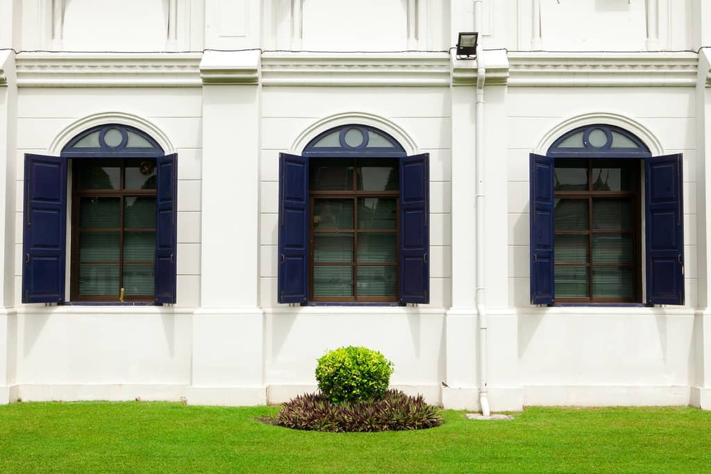 White home exterior with black awnings and potted plants