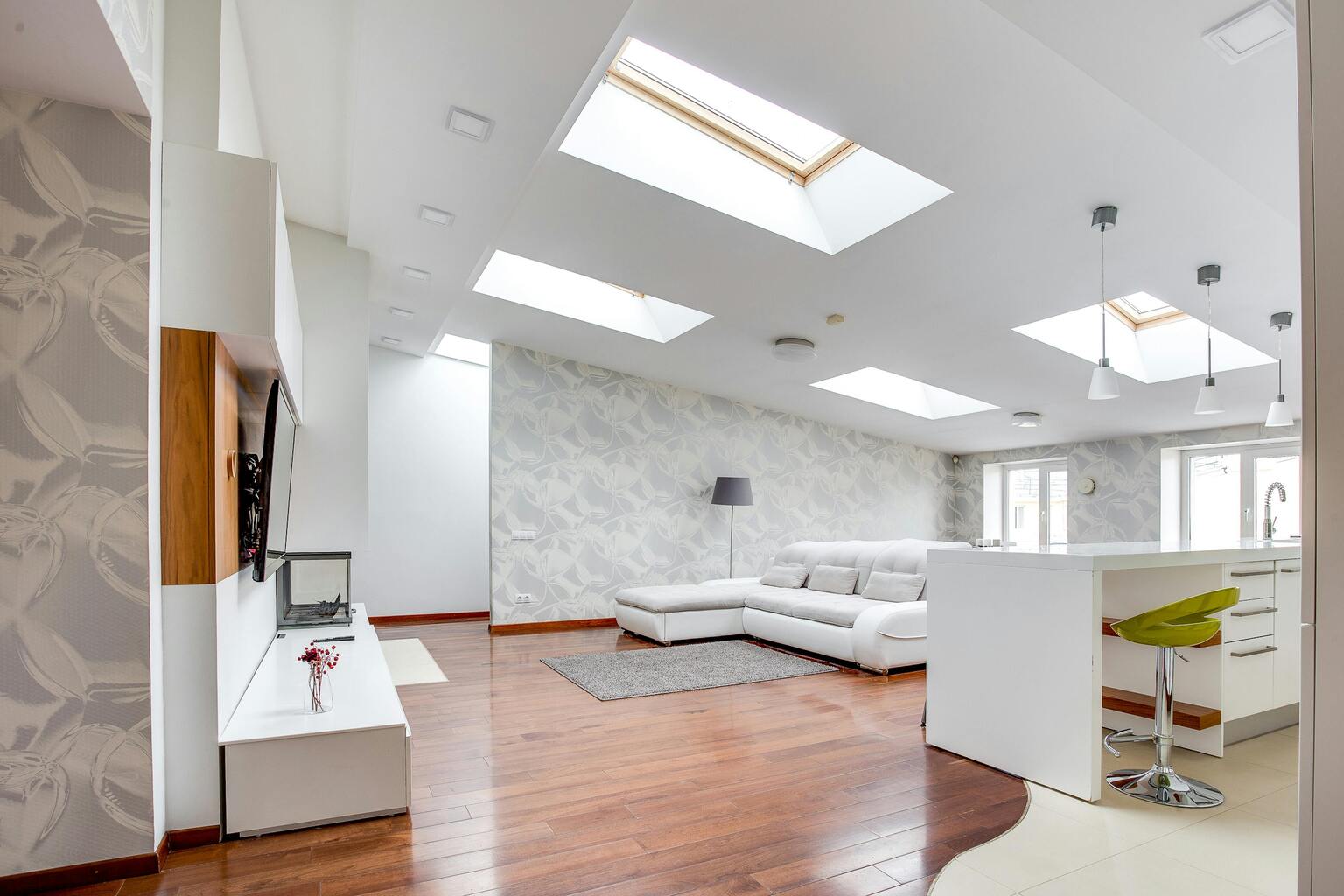 Modern living room with skylights, white sectional sofa, wooden flooring, and stylish decor, illustrating the benefits of natural light in home aesthetics.