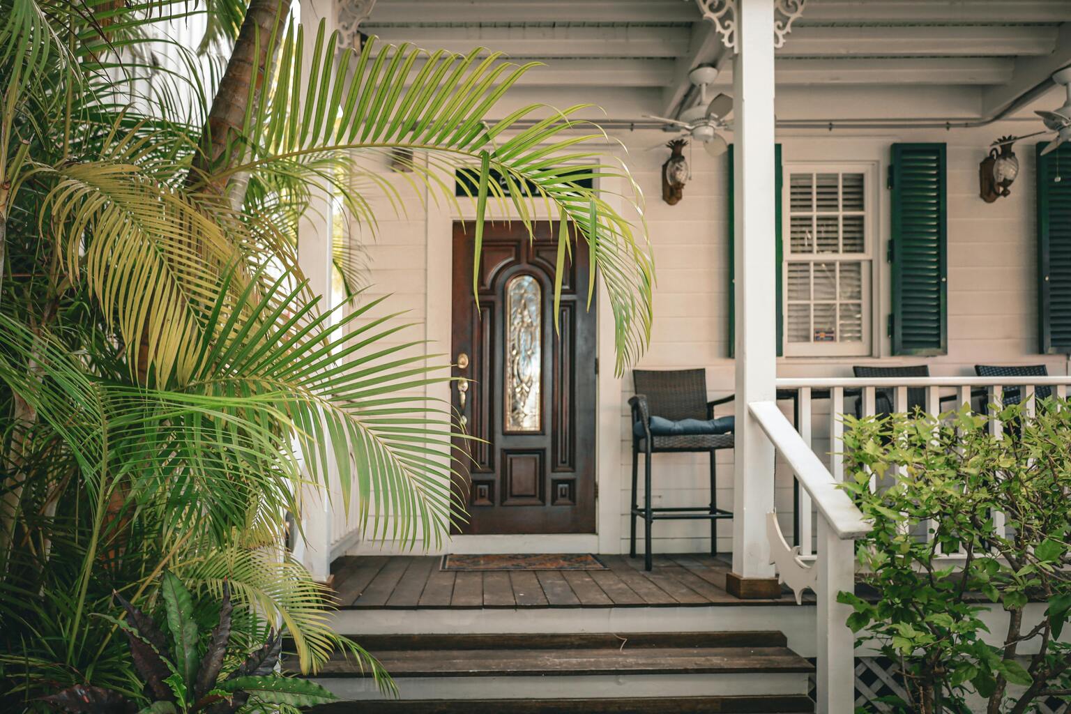 Cozy front porch with lush greenery, inviting wooden door, and seating area, showcasing potential for outdoor living enhancements by Tekton Exteriors.