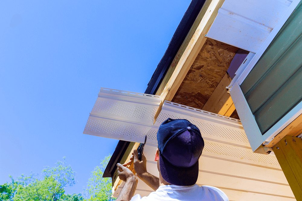 Person installing new siding panel on a residential home, showcasing quality craftsmanship and attention to detail, in the context of siding replacement services by Tekton Exteriors in Oxford, Mississippi.