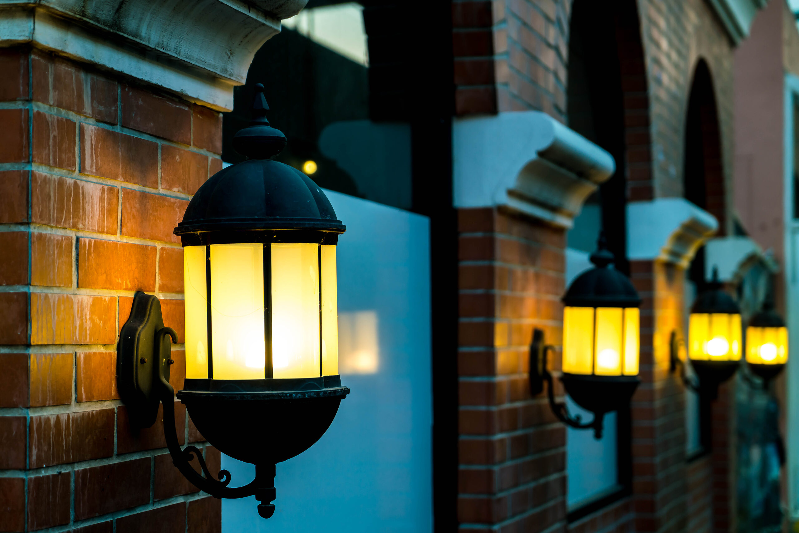 Outdoor wall lanterns illuminating a red brick wall, enhancing nighttime aesthetics and safety for outdoor spaces.