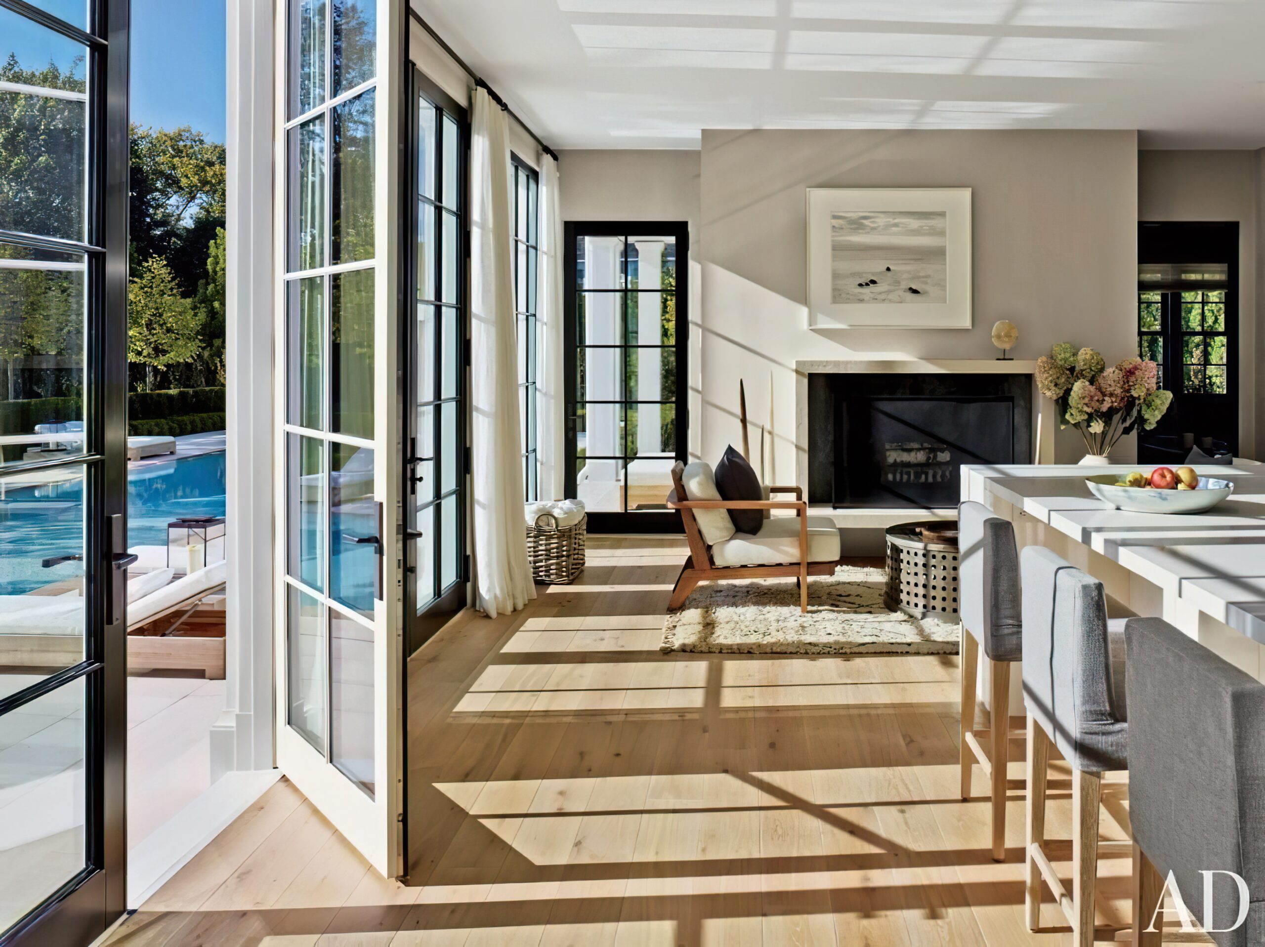 Bright living room featuring Pella sliding glass doors opening to a pool area, showcasing modern design, natural light, and a cozy fireplace.