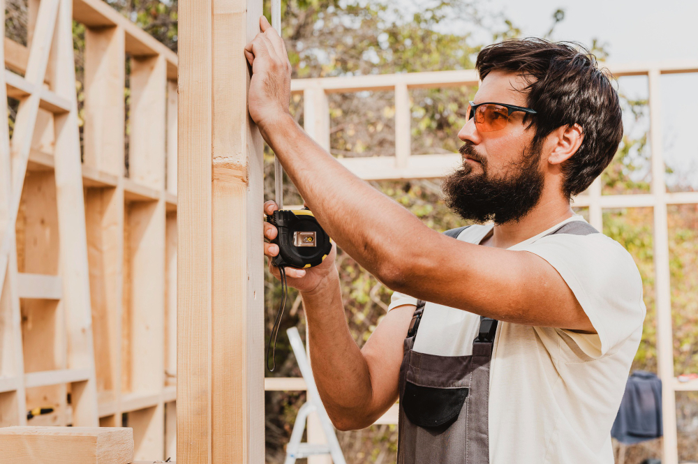 Skilled craftsman measuring wood framing for high-quality cedar and natural wood siding installation in Oxford, MS.